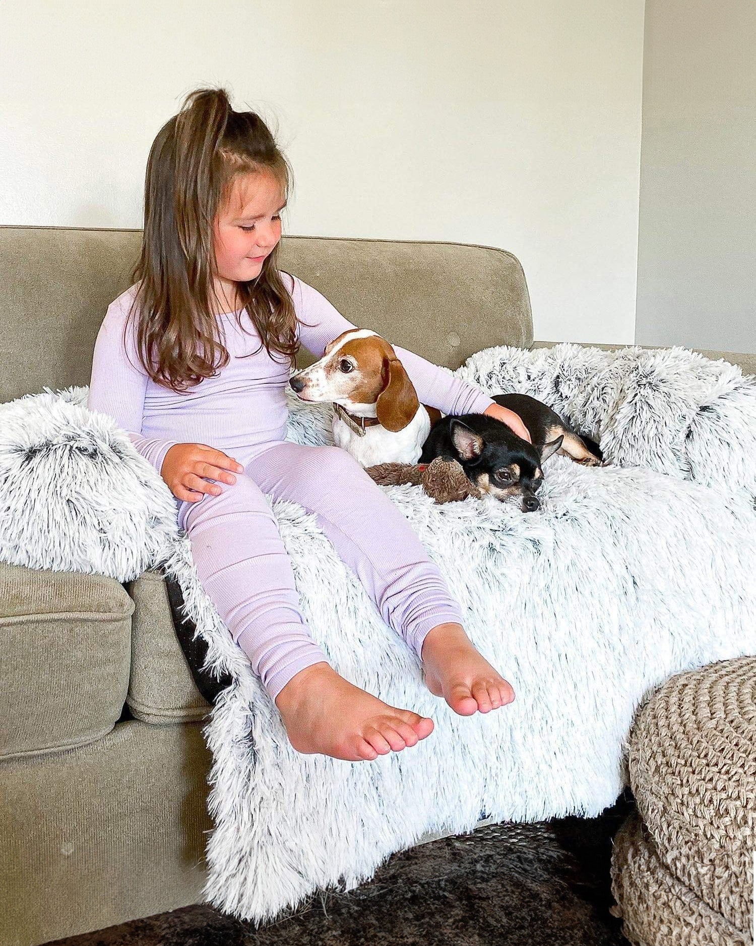 Bambina con due cani sul copridivano